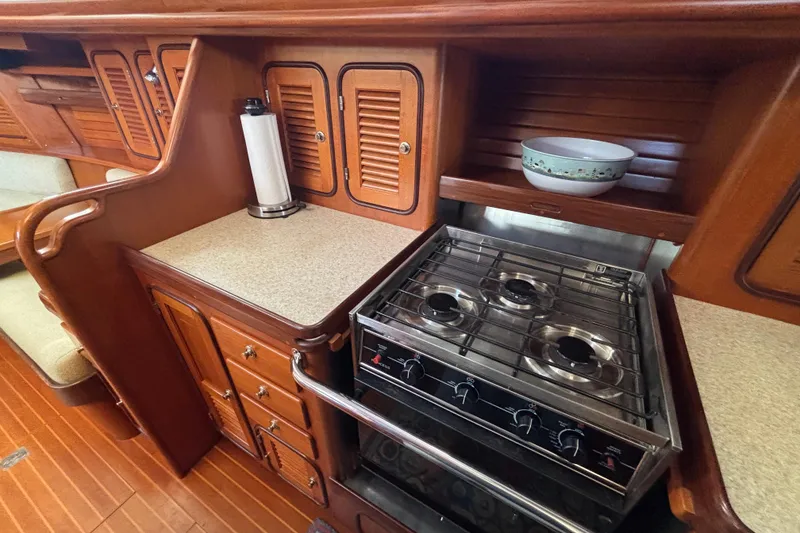 Slide: The Image of Wooden yacht kitchen with stove, cabinets, and countertop in a 2002 Passport 470 Center Cockpit. - 60