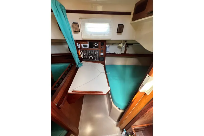 Slide: The Image of 1987 Island Packet SP Cruiser cabin interior with navigation station and teal cushions. - 46