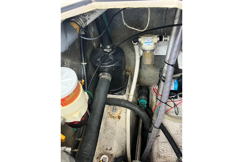 Slide: The Image of Engine compartment of a 1987 Island Packet SP Cruiser, showcasing hoses and filters. - 81