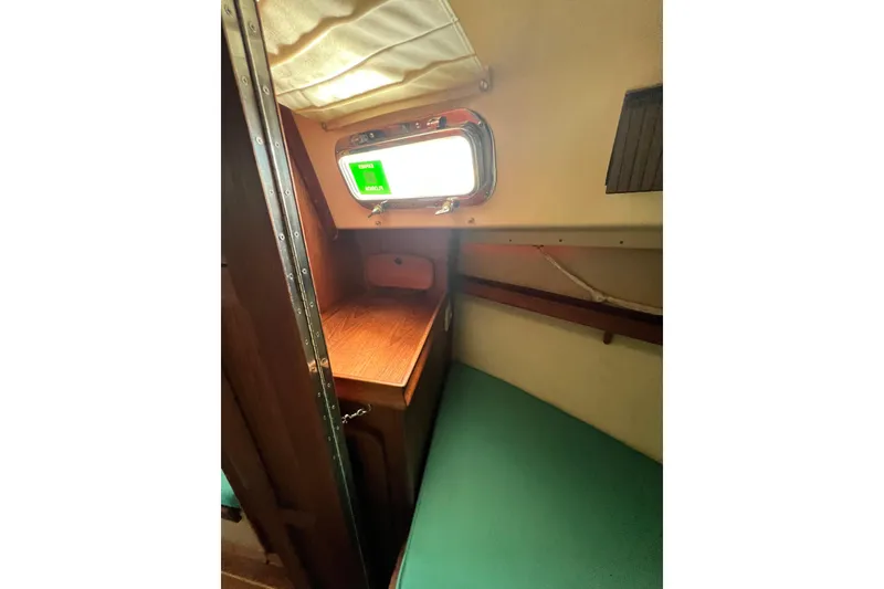 Slide: The Image of Cozy cabin interior of 1987 Island Packet SP Cruiser with wooden desk and green cushion. - 72