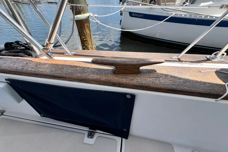 Slide: The Image of 1987 Island Packet SP Cruiser deck with wooden cleat and railing, docked beside another boat. - 25
