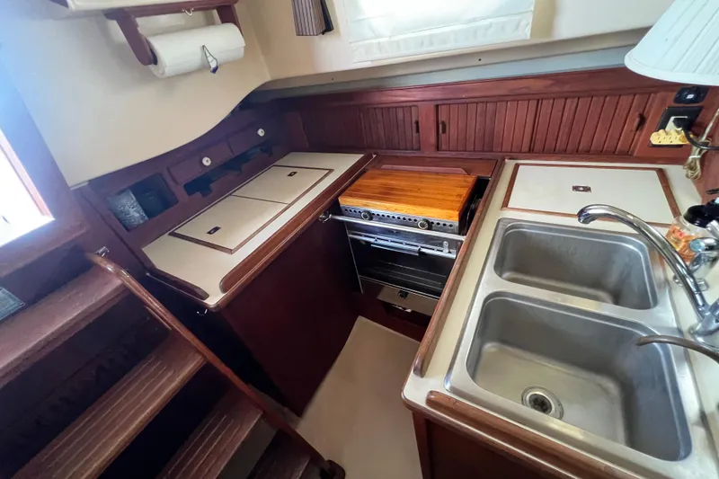 Slide: The Image of 1987 Island Packet SP Cruiser galley with stove, double sink, and wooden cabinetry. - 55