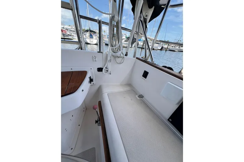 Slide: The Image of 1987 Island Packet SP Cruiser cockpit with marina view, showcasing seating and nautical equipment. - 32