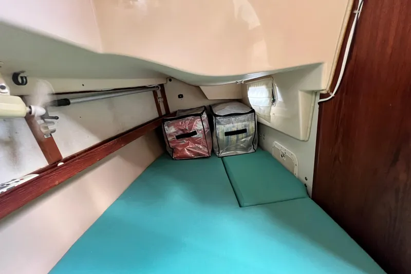 Slide: The Image of Cozy cabin interior of 1987 Island Packet SP Cruiser with teal cushions and storage bags. - 75