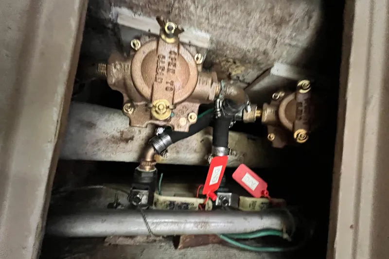 Slide: The Image of Engine compartment of 1987 Island Packet SP Cruiser showing plumbing and valves. - 83