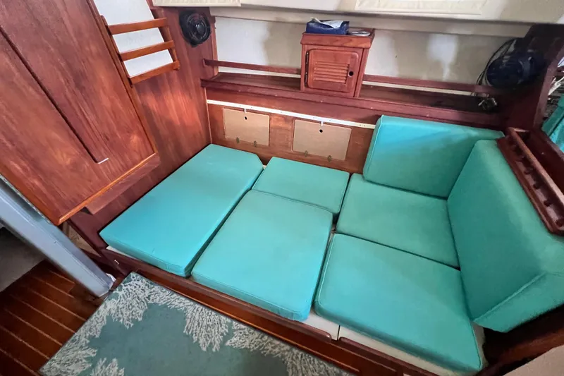 Slide: The Image of Interior of 1987 Island Packet SP Cruiser with teal cushions and wooden cabinetry. - 66