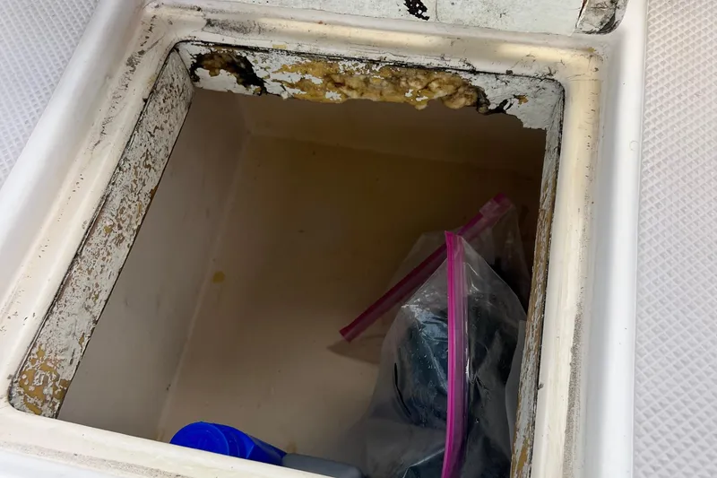 Slide: The Image of Storage compartment on 1987 Island Packet SP Cruiser with visible wear and stored items. - 38
