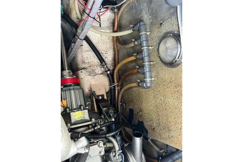Slide: The Image of Engine compartment of a 1987 Island Packet SP Cruiser with visible wiring and hoses. - 82
