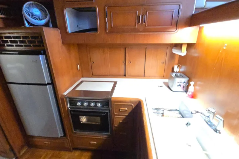 Slide: The Image of 1990 Pace 42 yacht kitchen with stove, fridge, and wooden cabinetry. - 39