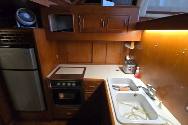 Slide: The Image of Compact kitchen in a 1990 Pace 42 boat with wooden cabinetry and modern appliances. - 38