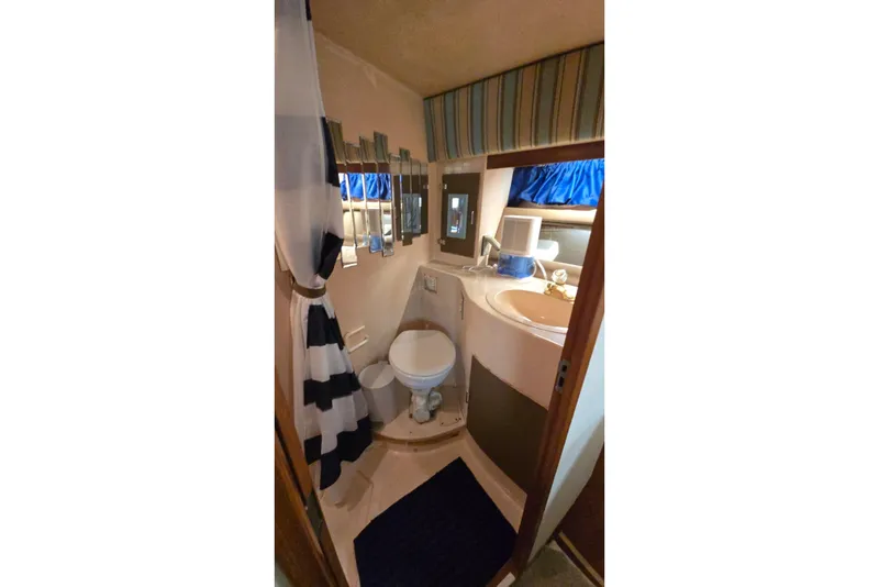 Slide: The Image of Compact bathroom in a 1990 Pace 42 boat with striped curtain and mirror accents. - 49