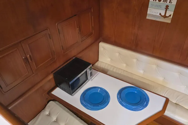 Slide: The Image of Cozy 1990 Pace 42 yacht interior with microwave, blue plates, and cushioned seating. - 42