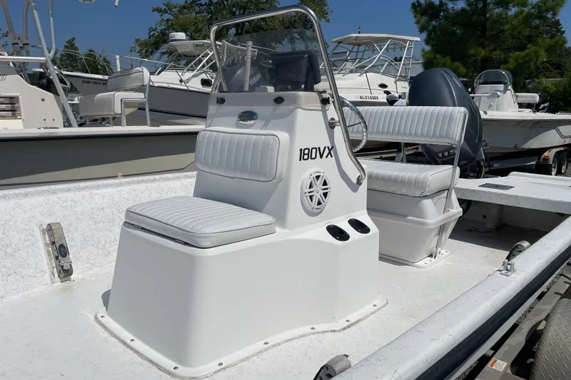Slide: The Image of 2006 Kenner 180 VX boat with white seating and console, parked among other boats. - 10