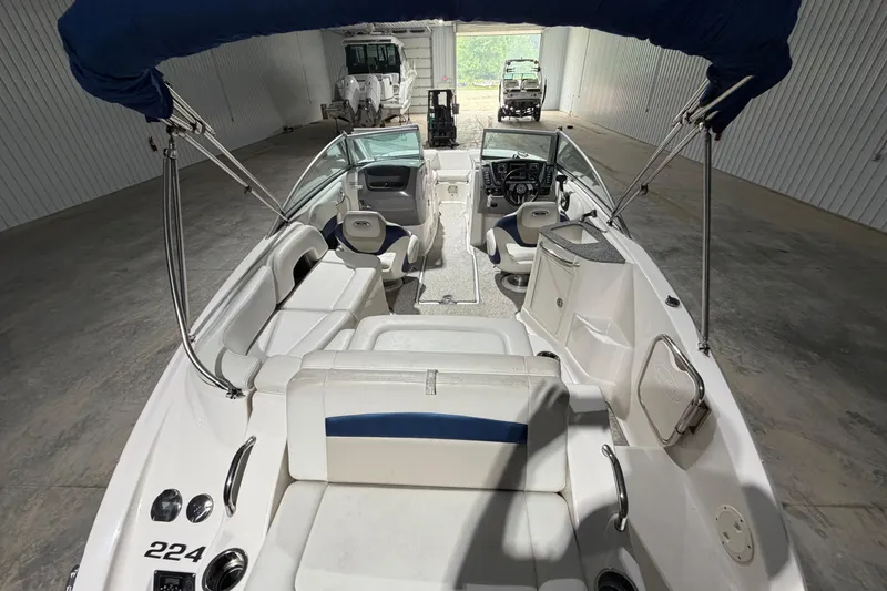 Slide: The Image of 2013 Chaparral 224 Sunesta boat interior with seating and steering wheel in a storage facility. - 7