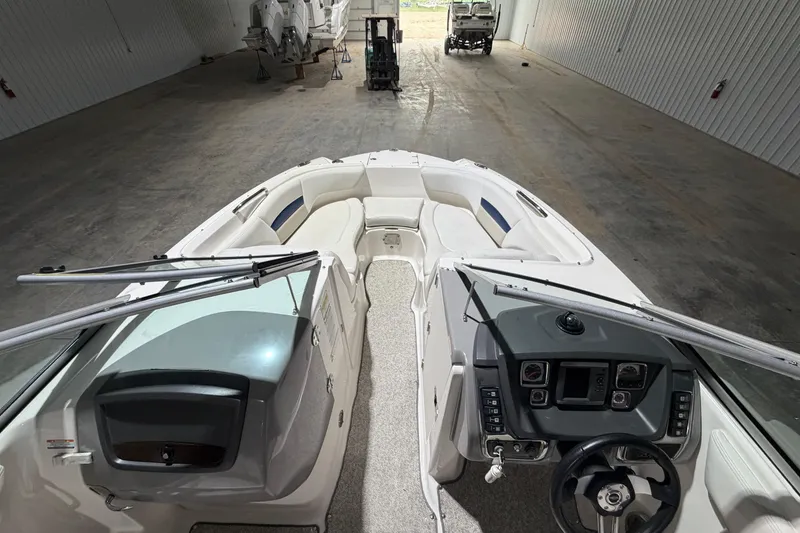 Slide: The Image of 2013 Chaparral 224 Sunesta boat interior with steering wheel and seating in a storage facility. - 11