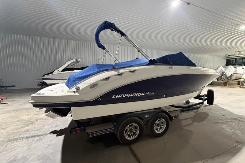 Slide: The Image of 2013 Chaparral 224 Sunesta boat with blue cover in indoor storage. - 17