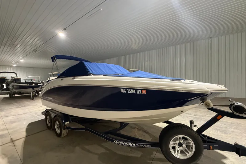 Slide: The Image of 2013 Chaparral 224 Sunesta boat with blue cover on trailer in storage facility. - 16