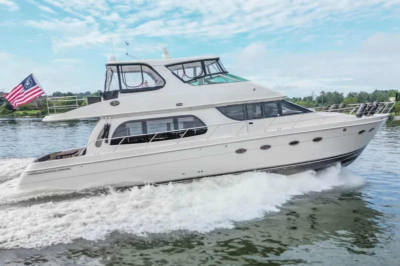 Slide: The Image of 2005 Carver 56 Voyager yacht cruising on a scenic waterway with American flag. - 9