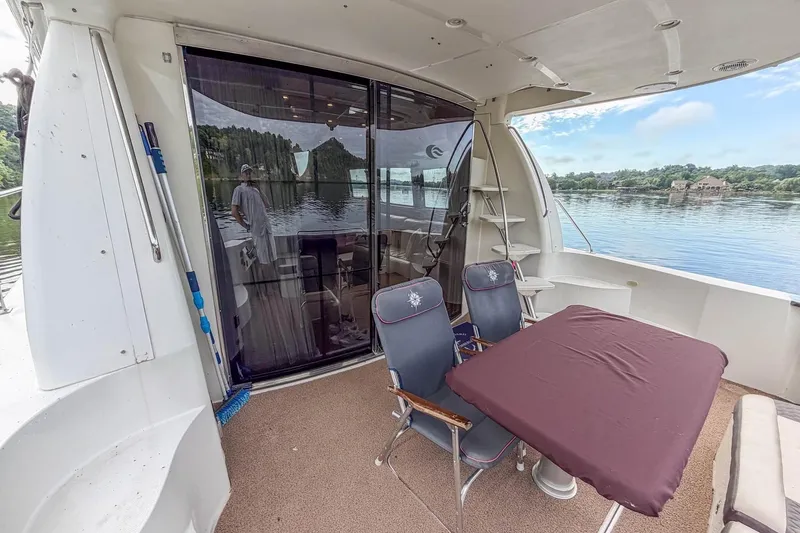 Slide: The Image of 2005 Carver 56 Voyager yacht deck with chairs, table, and scenic water view. - 37