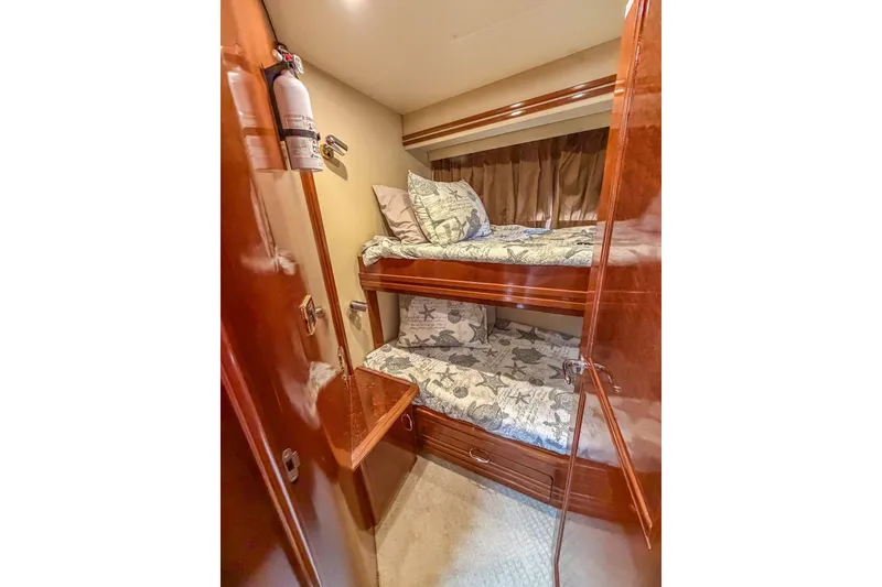 Slide: The Image of 2005 Carver 56 Voyager cabin with wooden bunk beds and nautical-themed bedding. - 16