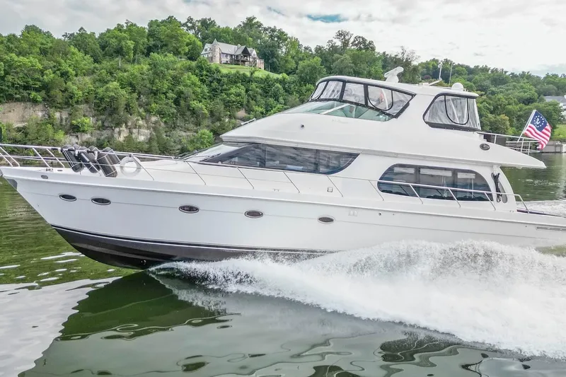 Slide: The Image of 2005 Carver 56 Voyager yacht cruising on a scenic river with lush greenery. - 11