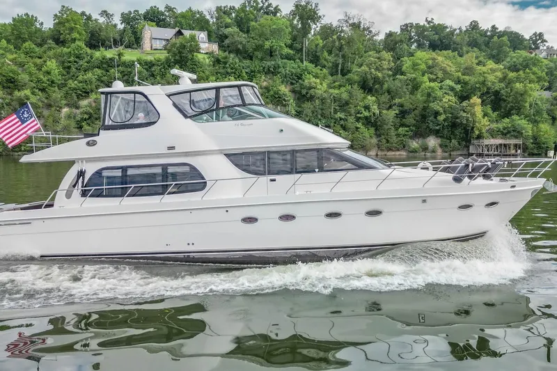 Slide: The Image of 2005 Carver 56 Voyager yacht cruising on a scenic river with lush greenery. - 7