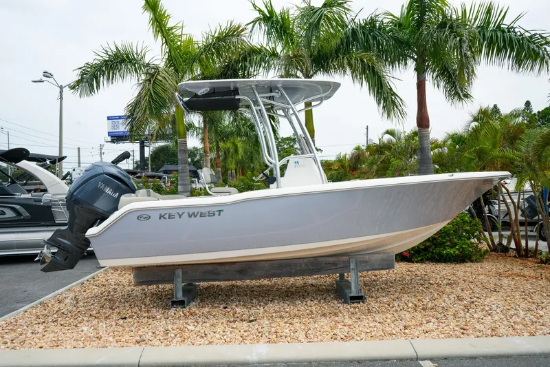 The Image of 2026 Key West 203 FS boat displayed outdoors with Yamaha engine, surrounded by palm trees. - 1
