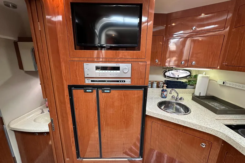 Slide: The Image of Luxurious 2008 Regal Commodore 4060 yacht interior with wood cabinetry, TV, and kitchenette. - 18