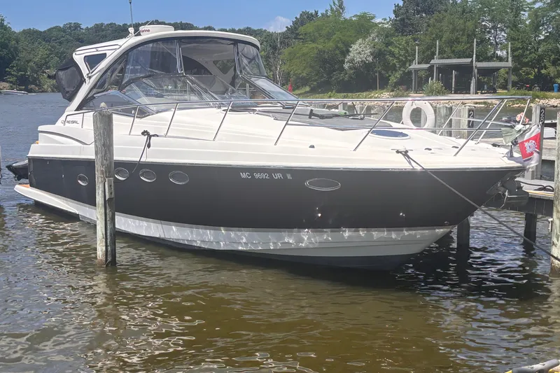 Slide: The Image of 2008 Regal Commodore 4060 boat docked on a sunny day, surrounded by water and greenery. - 0