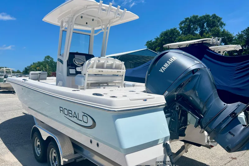 Slide: The Image of 2026 Robalo 246 Cayman boat with Yamaha engine, parked on a trailer under clear blue sky. - 3