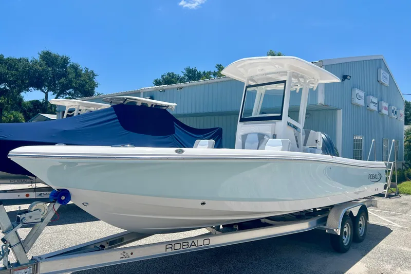 The Image of 2026 Robalo 246 Cayman boat on trailer, parked outdoors near a building. - 1