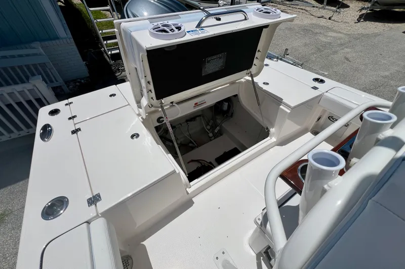 Slide: The Image of 2026 Robalo 246 Cayman boat interior with open storage compartment and rod holders. - 11