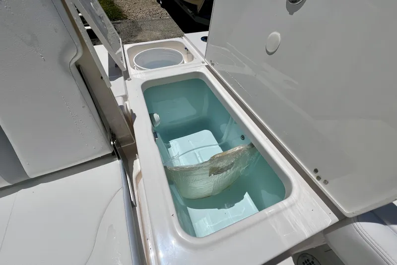 Slide: The Image of 2026 Robalo 246 Cayman boat storage compartment with open lid, showcasing interior space. - 10