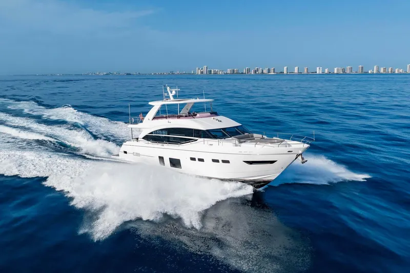 Slide: The Image of Luxurious 2018 Princess Y75 yacht cruising on open sea with city skyline in background. - 77