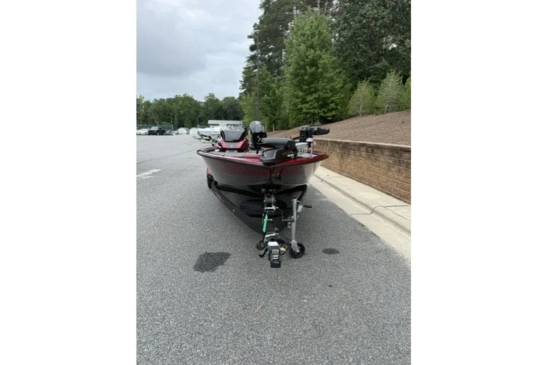Slide: The Image of 2027 Vexus AVX1880 boat on trailer, parked on a paved road with trees in background. - 2