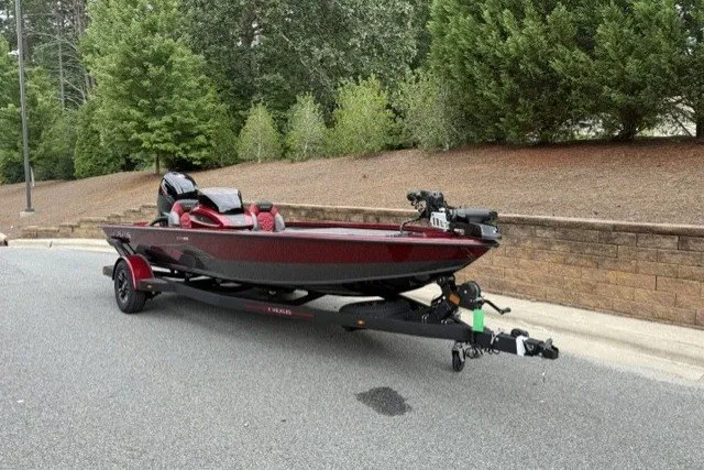 Slide: The Image of 2027 Vexus AVX1880 boat on trailer, parked on road with lush greenery background. - 1