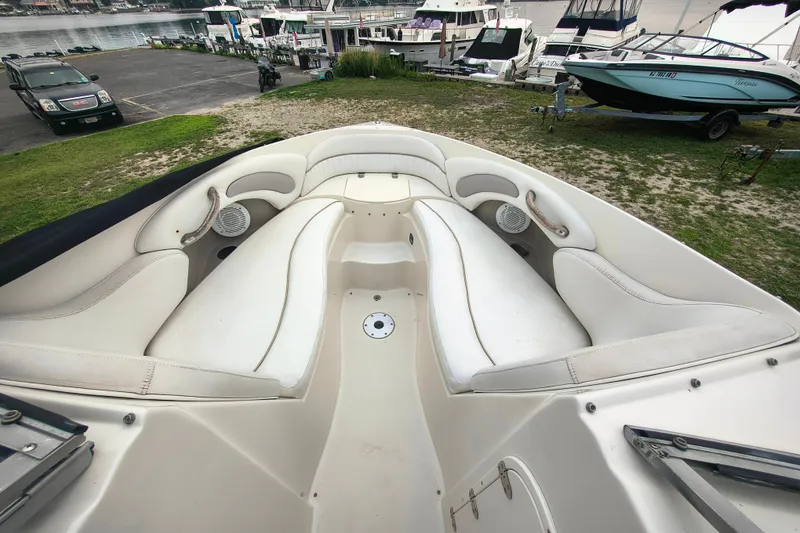 Slide: The Image of 2006 Stingray 250 LR boat interior with white seating, docked near other boats. - 10