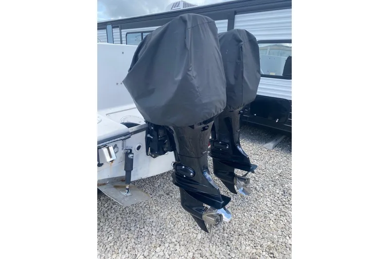 Slide: The Image of Twin outboard motors on a 1994 Robalo 2440 Walkaround, covered and parked on gravel. - 2