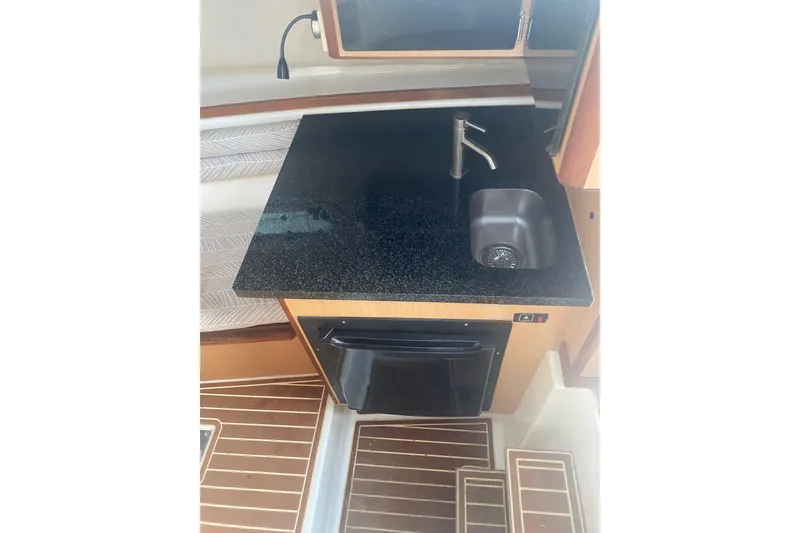 Slide: The Image of 1994 Robalo 2440 Walkaround boat interior with compact kitchenette and sink. - 13