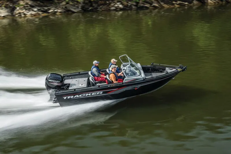 The Image of A black Tracker boat speeds along a river, with two people on board. - 18