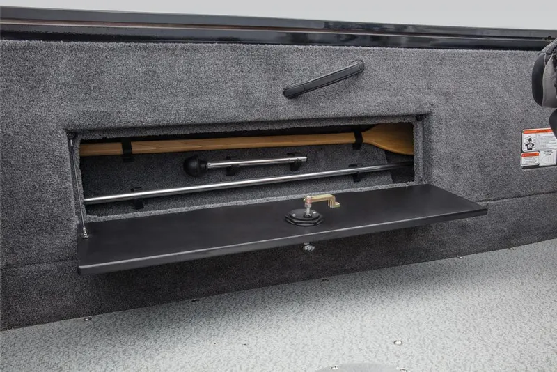 Slide: The Image of An open storage compartment in the boat with gray carpeting and a black lid. - 46