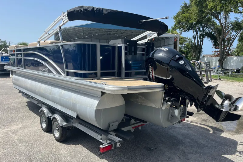 Slide: The Image of 2024 Harris Cruiser 230 pontoon boat on trailer, featuring sleek design and powerful outboard motor. - 6