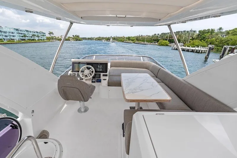 Slide: The Image of Flybridge of 2022 Azimut Fly 50 yacht with helm, seating, and table, cruising on a scenic waterway. - 22