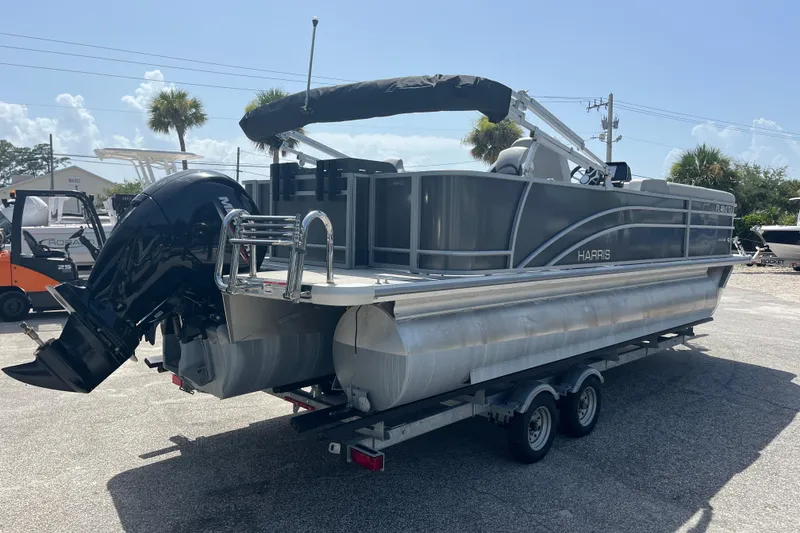 Slide: The Image of 2024 Harris Cruiser 230 pontoon boat on trailer, featuring sleek design and powerful outboard motor. - 4