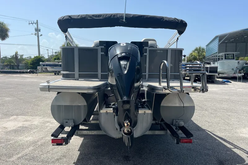 Slide: The Image of 2024 Harris Cruiser 230 pontoon boat with outboard motor, parked outdoors. - 5