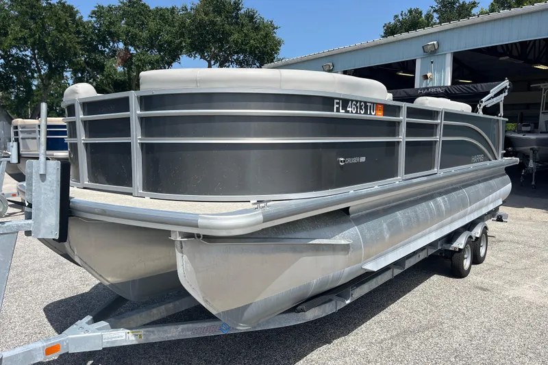 The Image of 2024 Harris Cruiser 230 pontoon boat on trailer, parked outdoors near a building. - 0