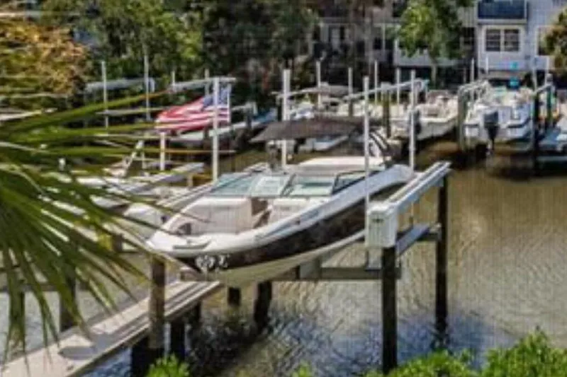 Slide: The Image of A 2020 Sea Ray SPX 230 Outboard is on a boat lift in a tranquil marina. - 1