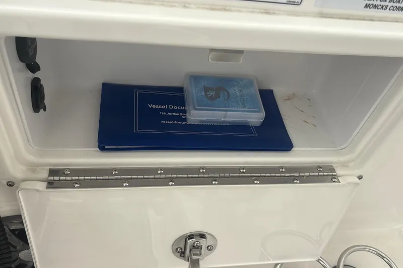 Slide: The Image of Storage compartment on 2023 Sea Fox 268 Traveler with vessel documents and a small container. - 24