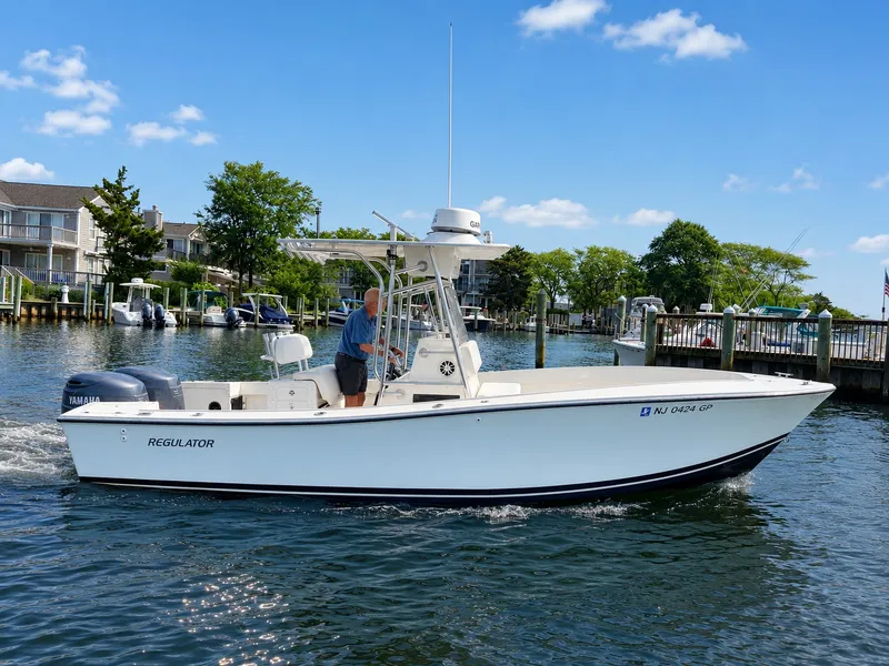 The Image of A 2000 Regulator Center Console 23 navigates calm waters. A man is steering the boat. - 0