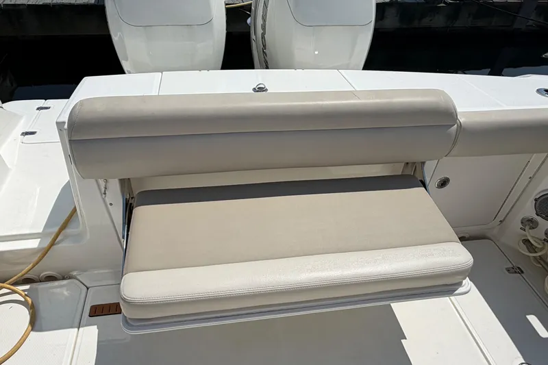 Slide: The Image of 2017 Boston Whaler 330 Outrage boat seating area with cushioned bench and white deck. - 17